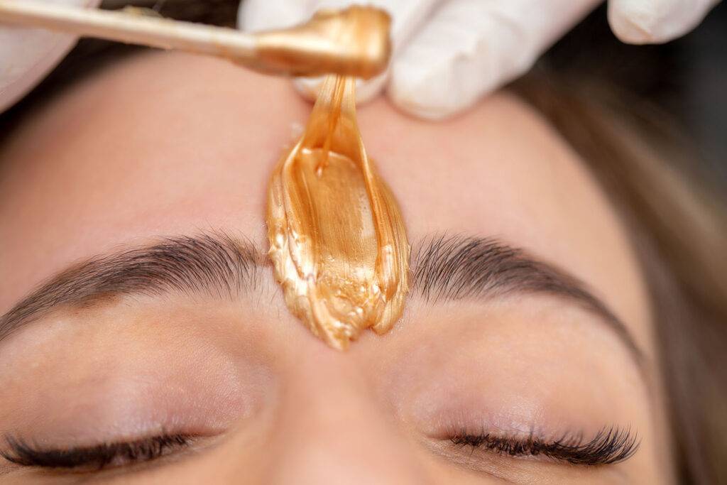 Applying Facial Wax Between Eyebrows - stock photo