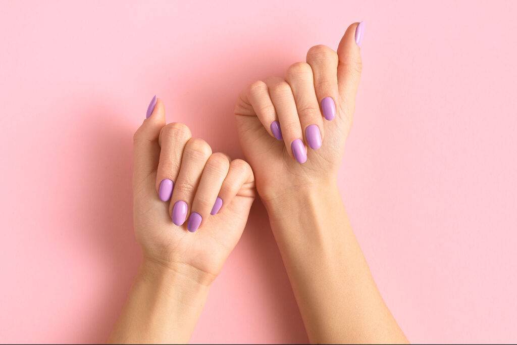 Womans hands with fashionable lavender manicure on pink background. Spring summer nail design